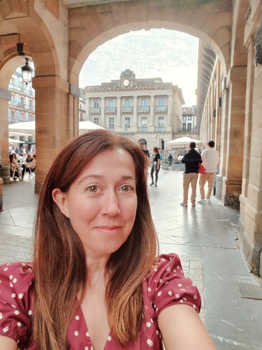 Challenge Fifty-Two, a white woman with dark hair smiling at the camera as she takes a selfie in a square in San Sebastián