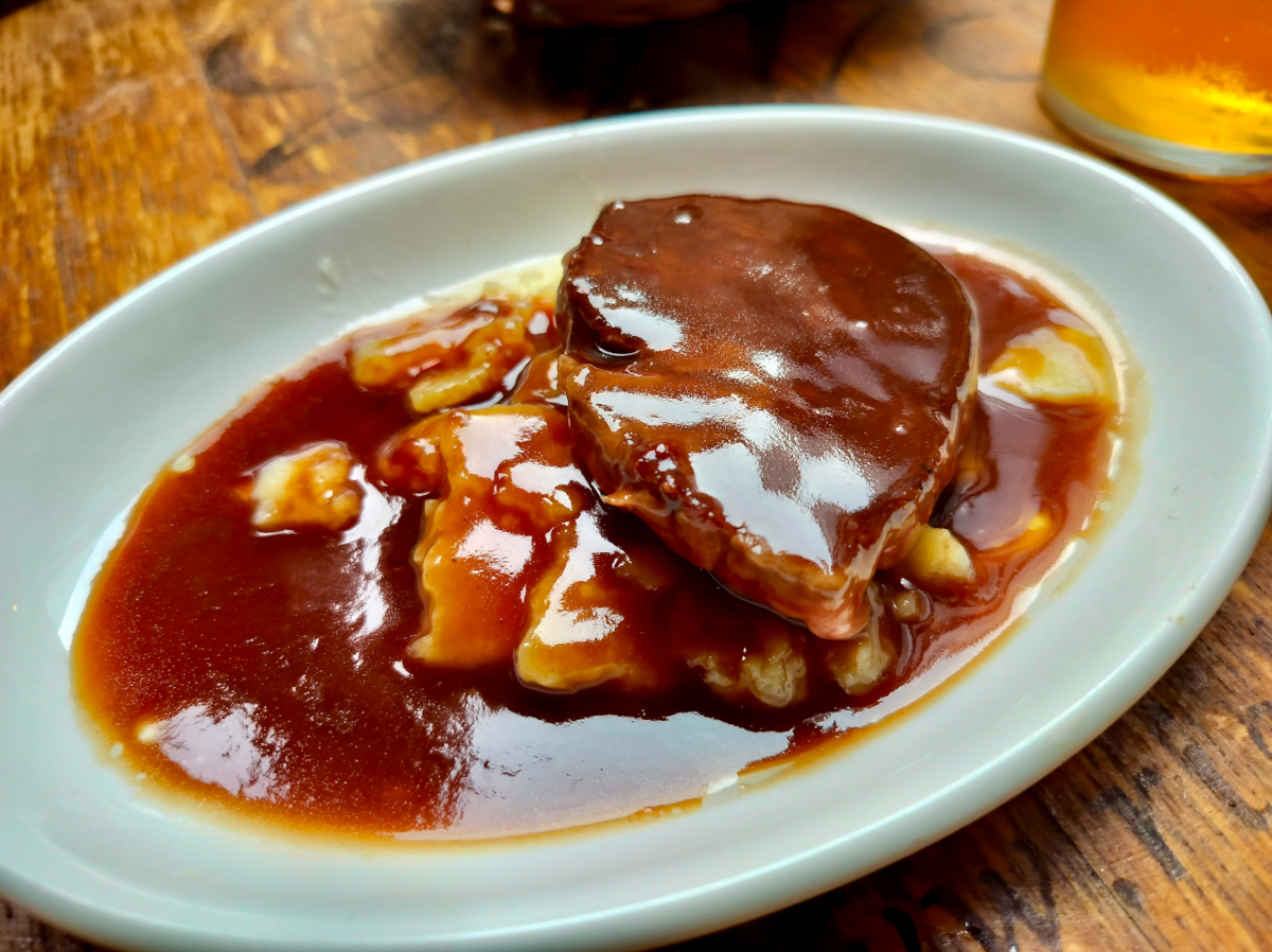 A delicious looking plate from a Pintxos Tour In San Sebastián. It contains a piece of steak on a bed of potatoes smothered with a rich port gravy