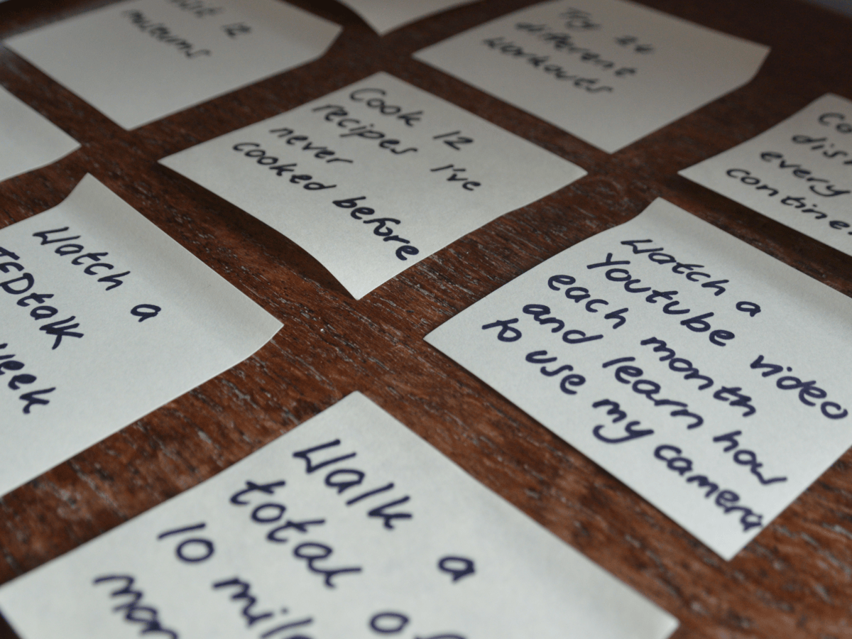 Post it notes with goals written on them. Each goal is specific. These are examples of how to set a new year's resolution you'll actually want to stick to