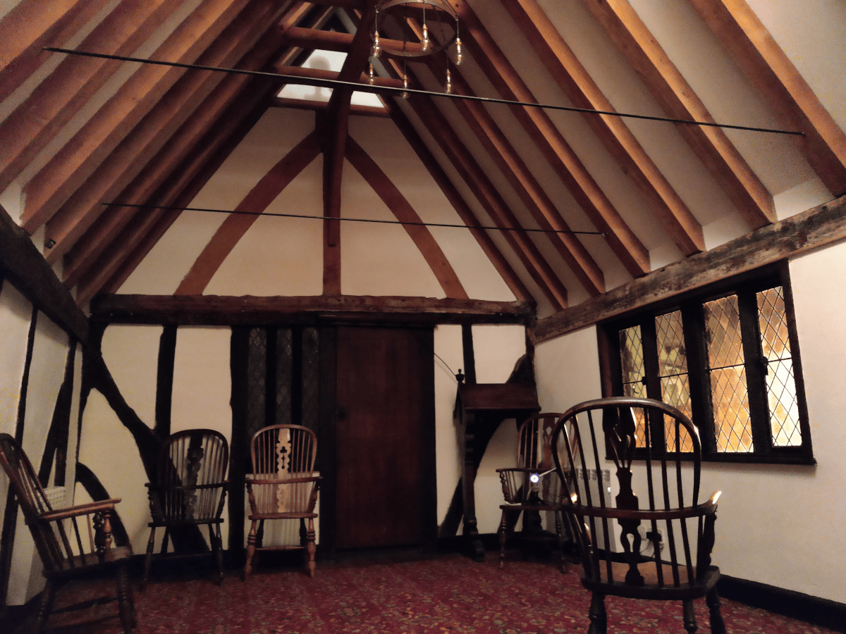 An interior shot of an old tudor building with white walls and wooden beams. Chairs are in the room.