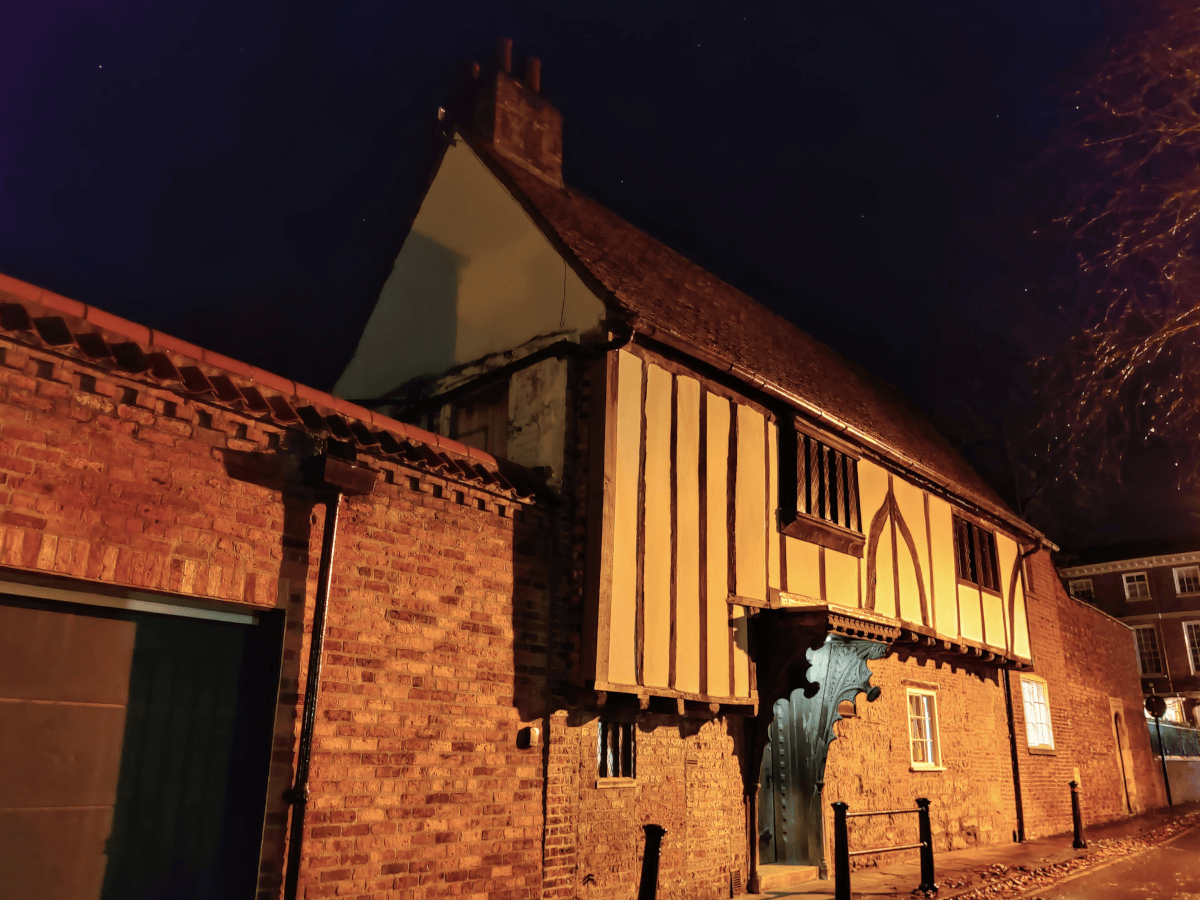Exterior picture of a Tudor building at night, with white walls and wooden beams. The venue for a spooky experience.