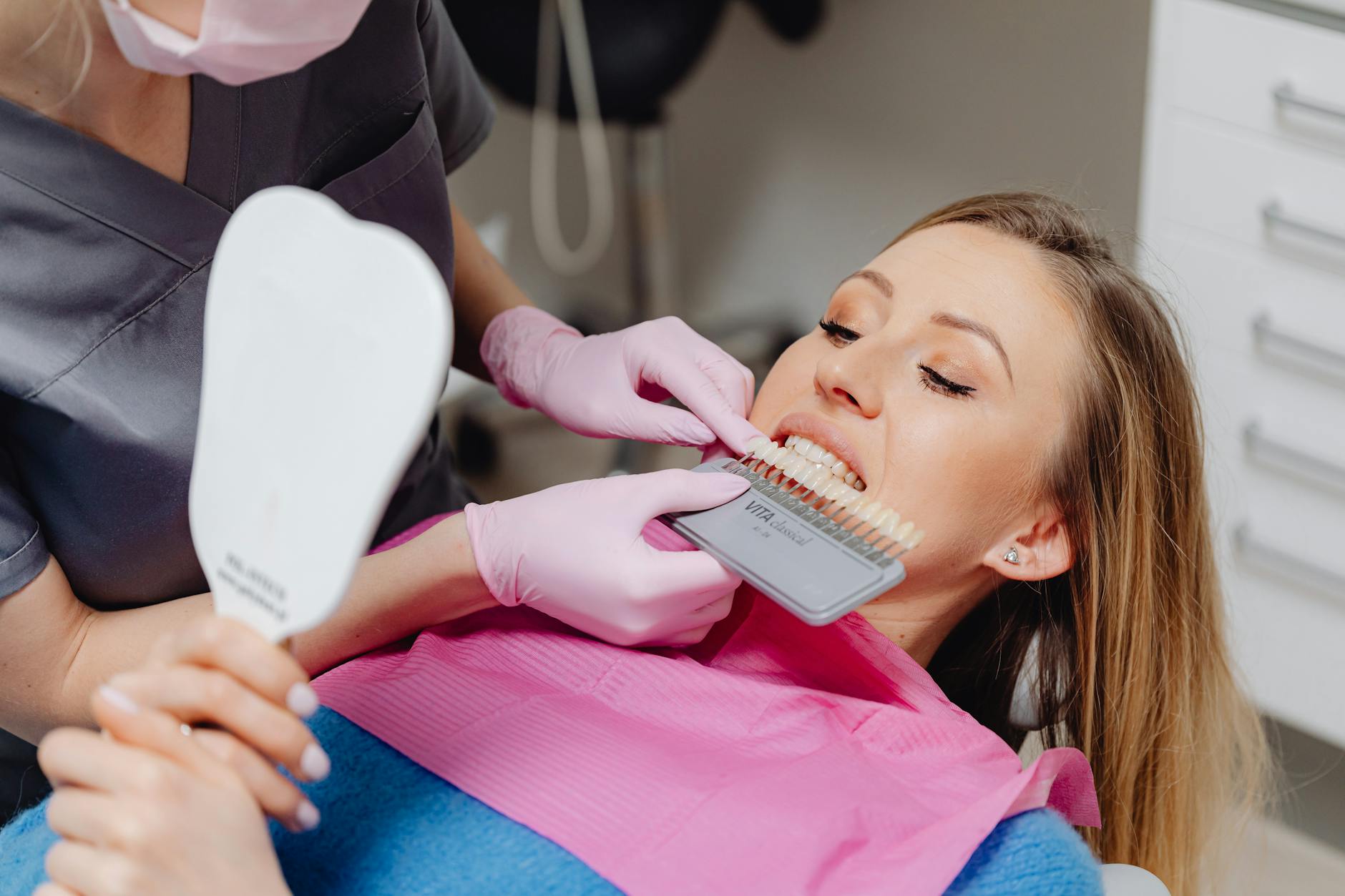 a dentist holding a dental shade guide in front of a patient