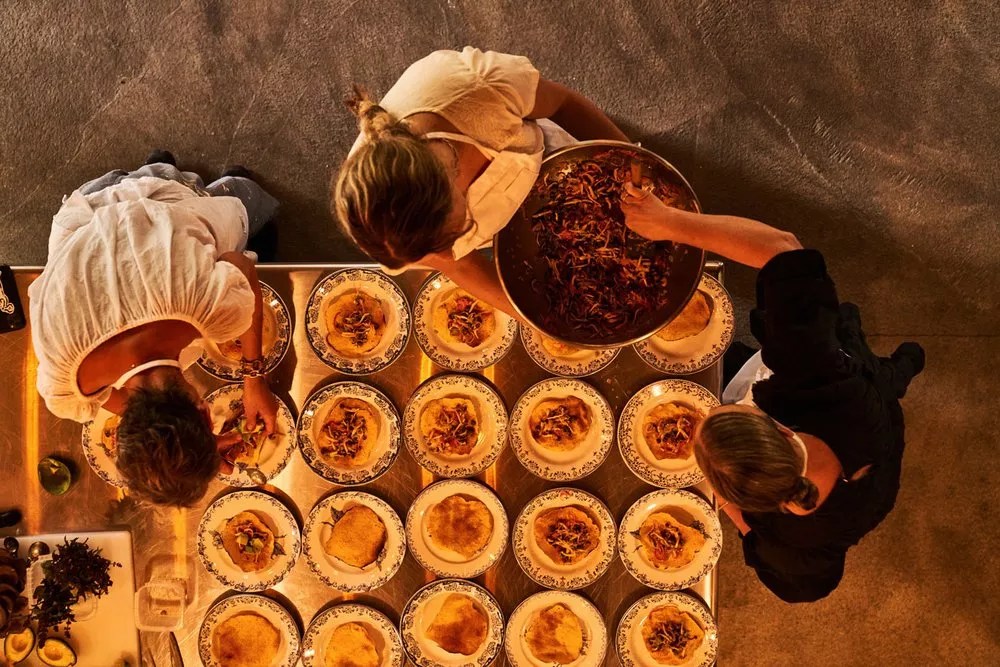 A top-down photo of a multiple people surrounding a dinner table.