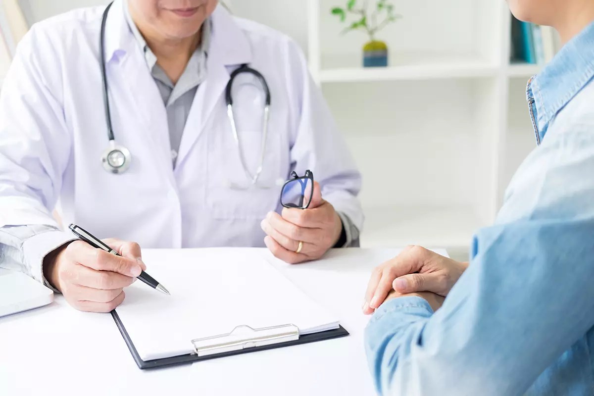 Paciente que escucha atentamente a un médico que le explica los síntomas del paciente o le hace una pregunta mientras discuten los papeles juntos en una consulta en la Clínica Hispana