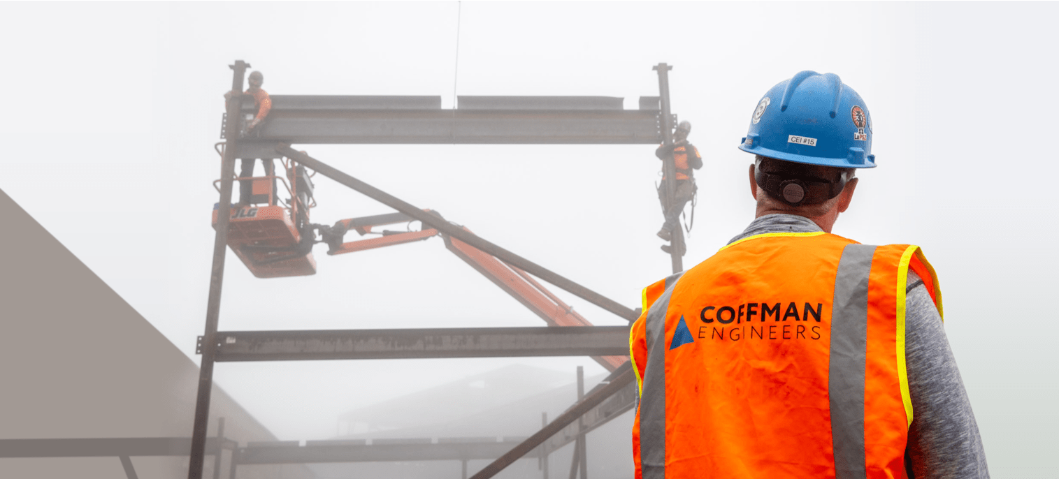A man wears an orange work vest with Coffman Engineers written on the back