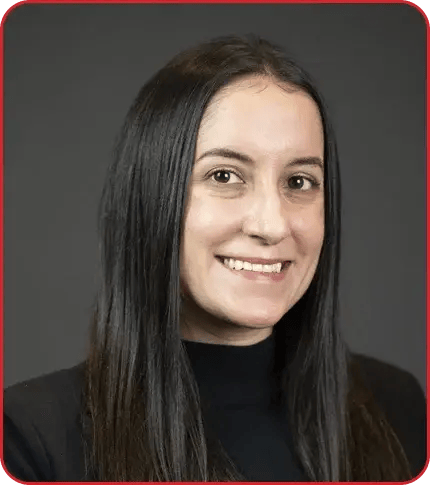 Professional headshot of a woman with long dark hair wearing a black turtleneck against a gray background
