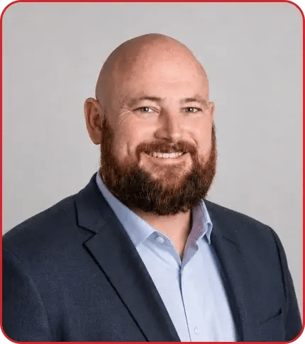 Professional headshot of Nickalis Powers, a bald man with a brown beard wearing a navy blazer and light blue shirt