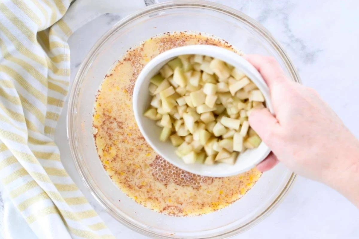 chopped apples being poured into an egg mixture