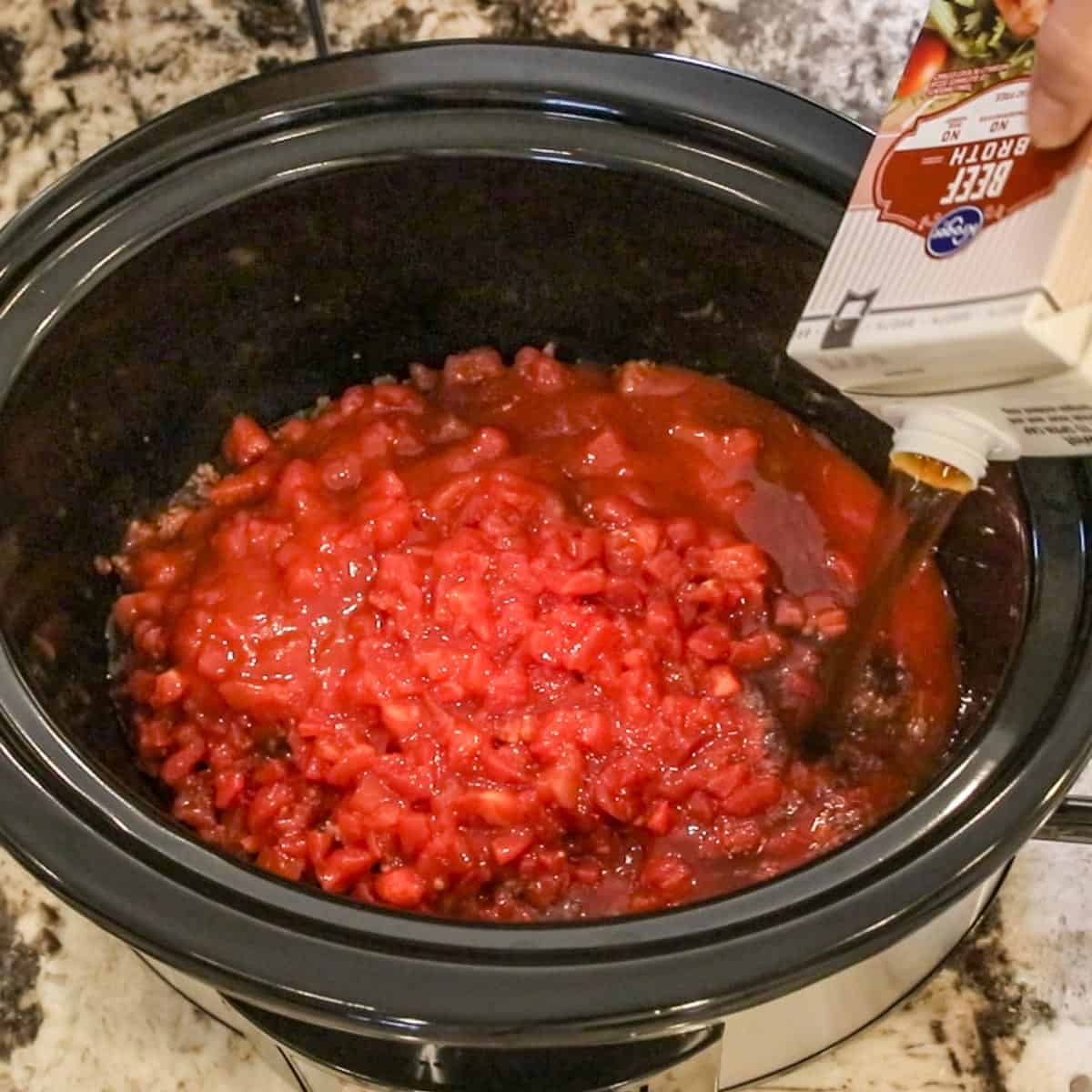 diced tomatoes and beef broth being added to a slow cooker