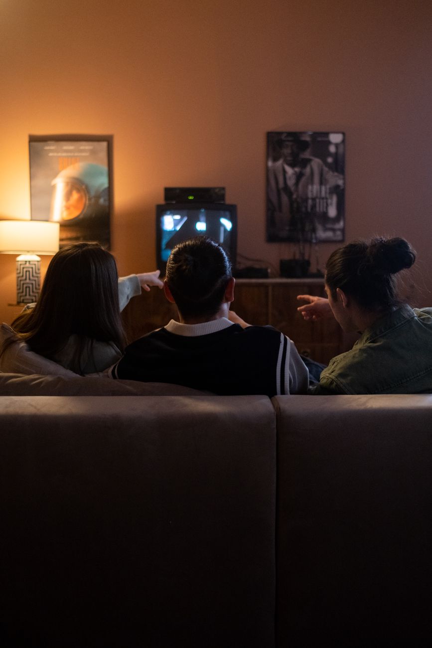 friends watching tv on the couch and pointing something at tv player