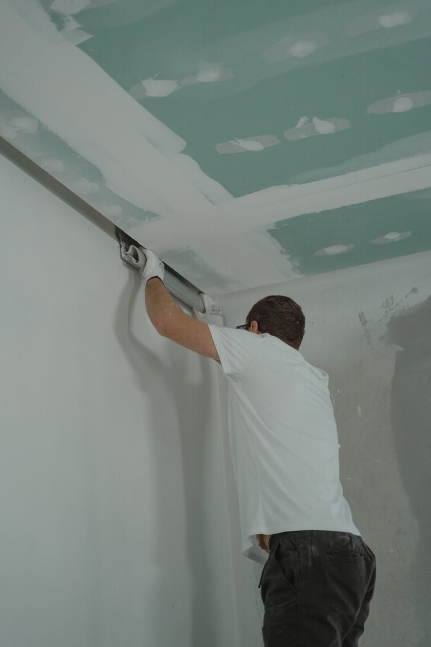 a man in white shirt painting a house