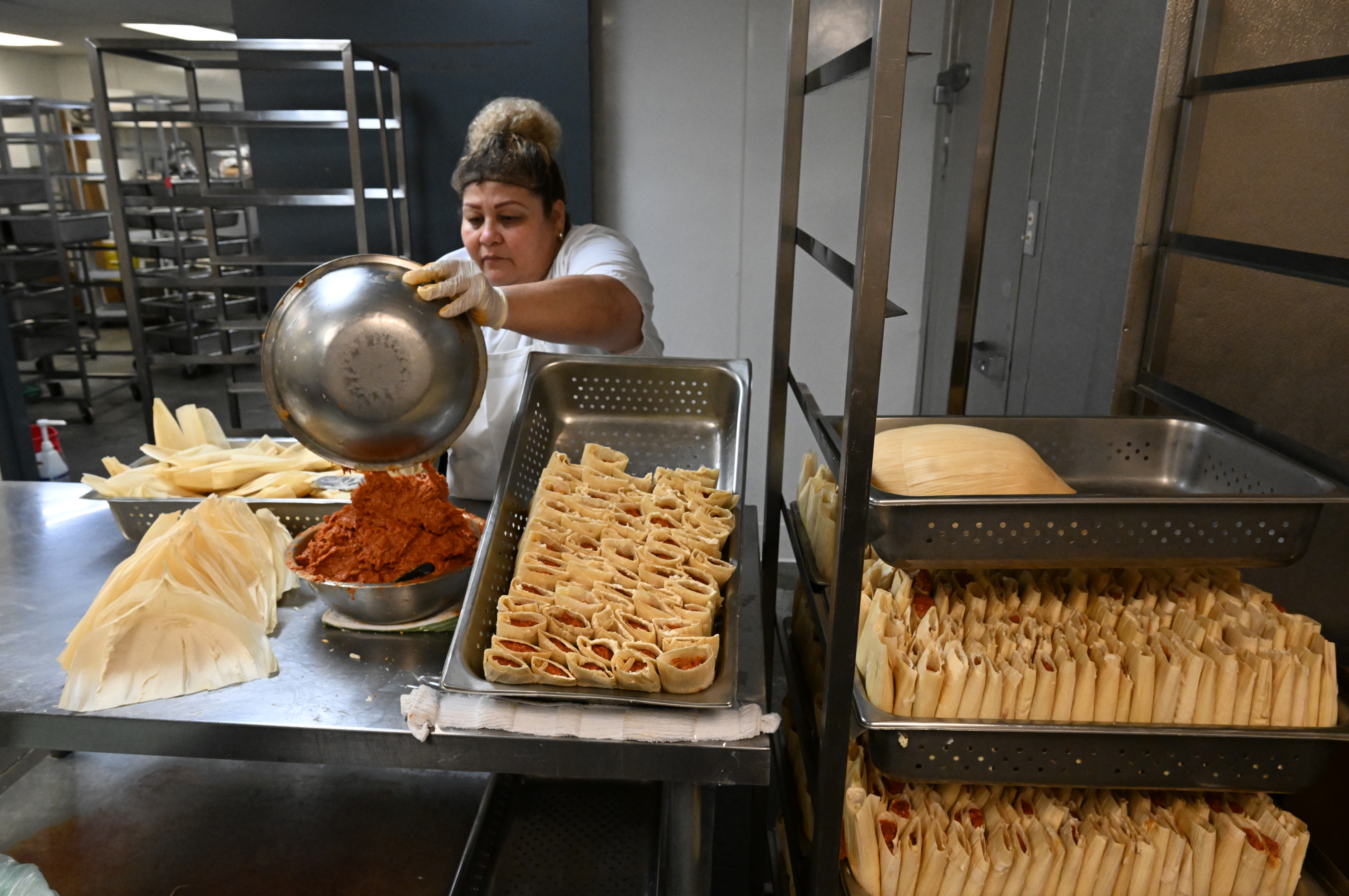 Rosa Dias fills a bowl with red chile and pork to make tamales by hand at Tamales by La Casita on Nov. 28, 2023, in Denver. (Photo by Helen H. Richardson/The Denver Post)