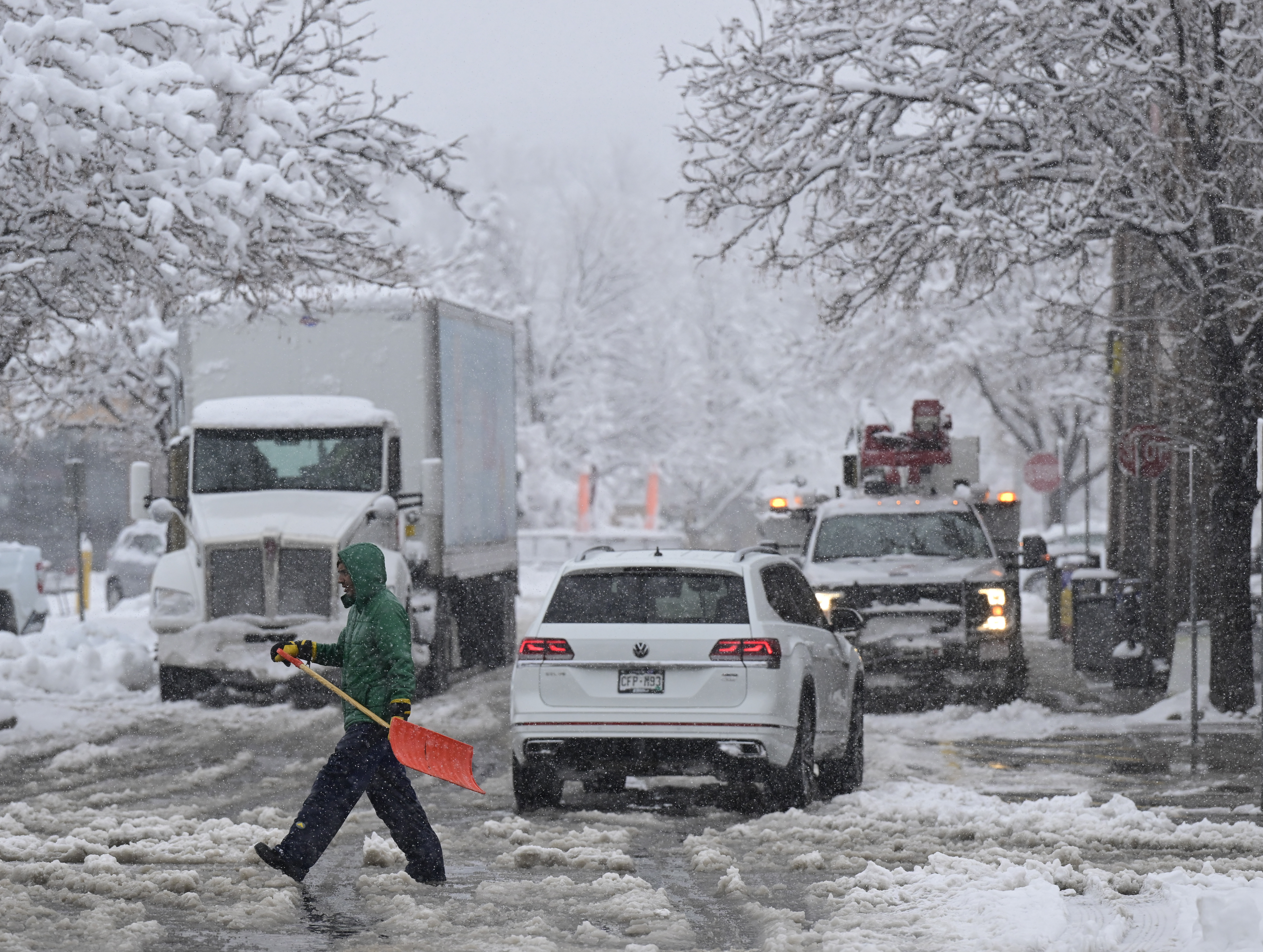 A worker with a snow shovel negotiates heavy, wet snow in the University Hills King Soopers parking lot in Denver on Thursday, March 14, 2024. (Photo by Andy Cross/The Denver Post)