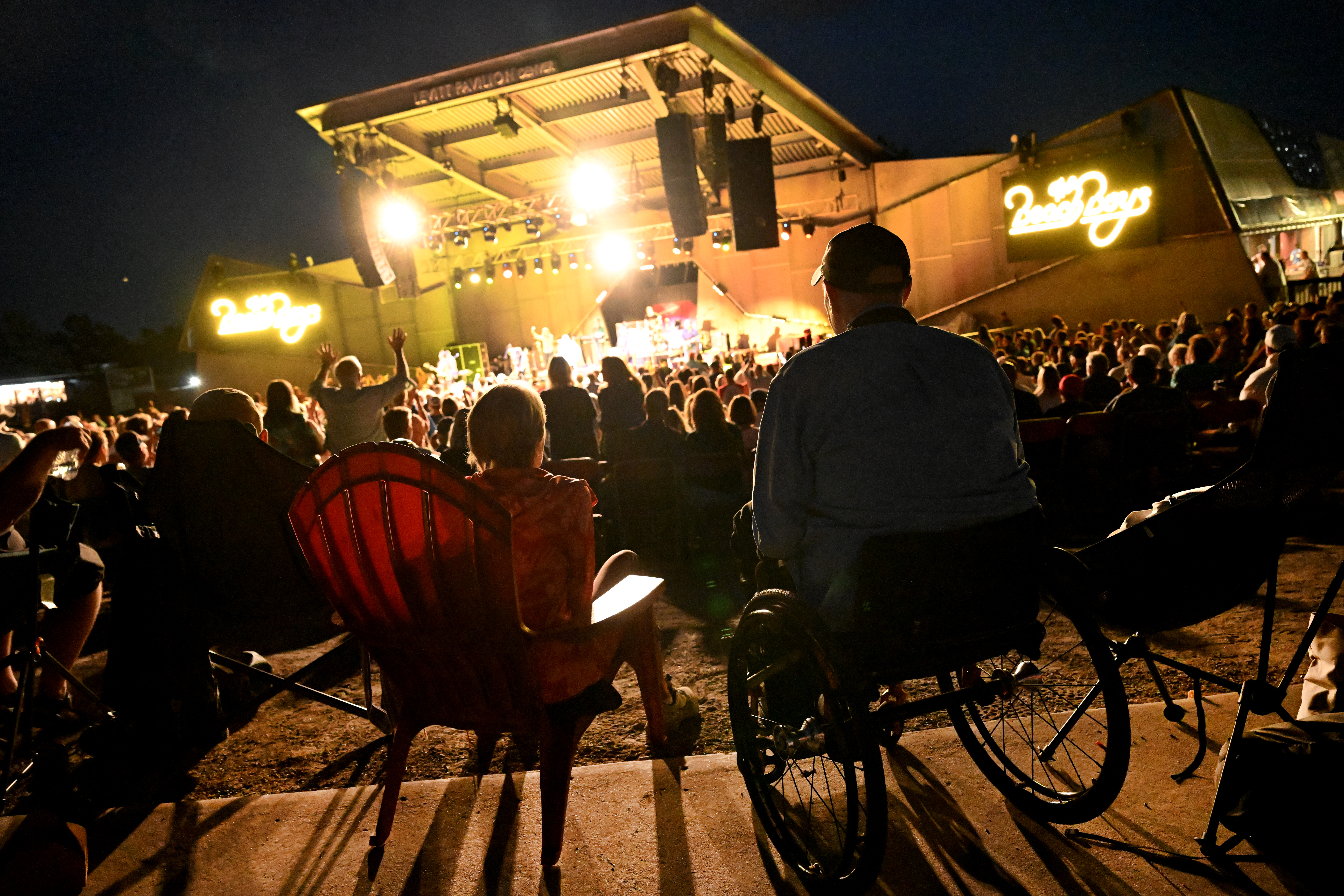 Bob Roark, right, and Penny Machmer, left, watch the Beach Boys perform from ADA accessible seating areas at Levitt Pavilion in Denver on Aug. 14, 2024. (Photo by Helen H. Richardson/The Denver Post)