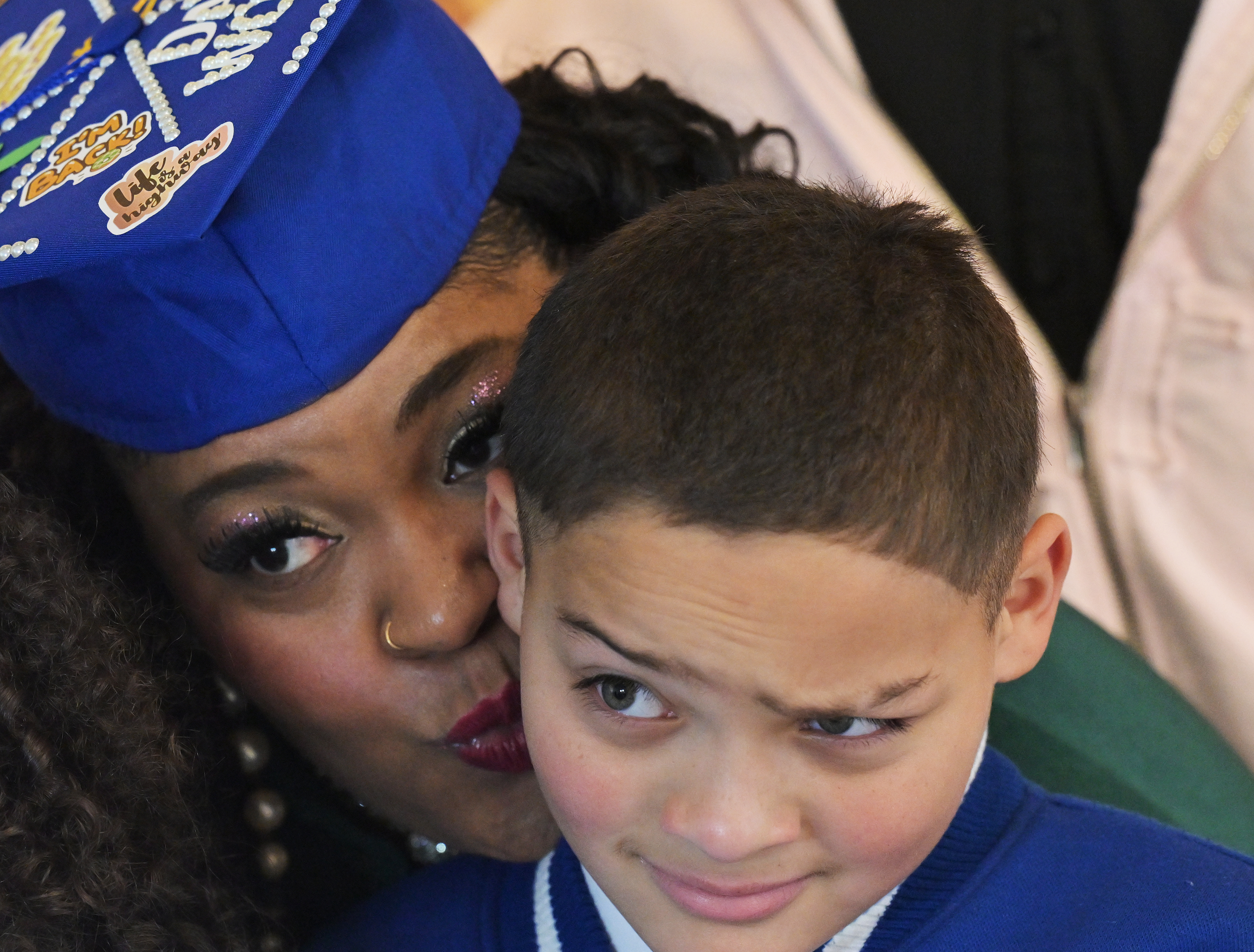 Nilka Kentish, graduate of Rocky Mountain Prep Peak Family Tutor program, goes to kiss her son Kai Tanner, 9, during a family photo before the ceremony in Denver on Feb. 10, 2025. Rocky Mountain Prep held a graduation ceremony at Colorado State University's Spur Hydro Building in Denver. (Photo by RJ Sangosti/The Denver Post)