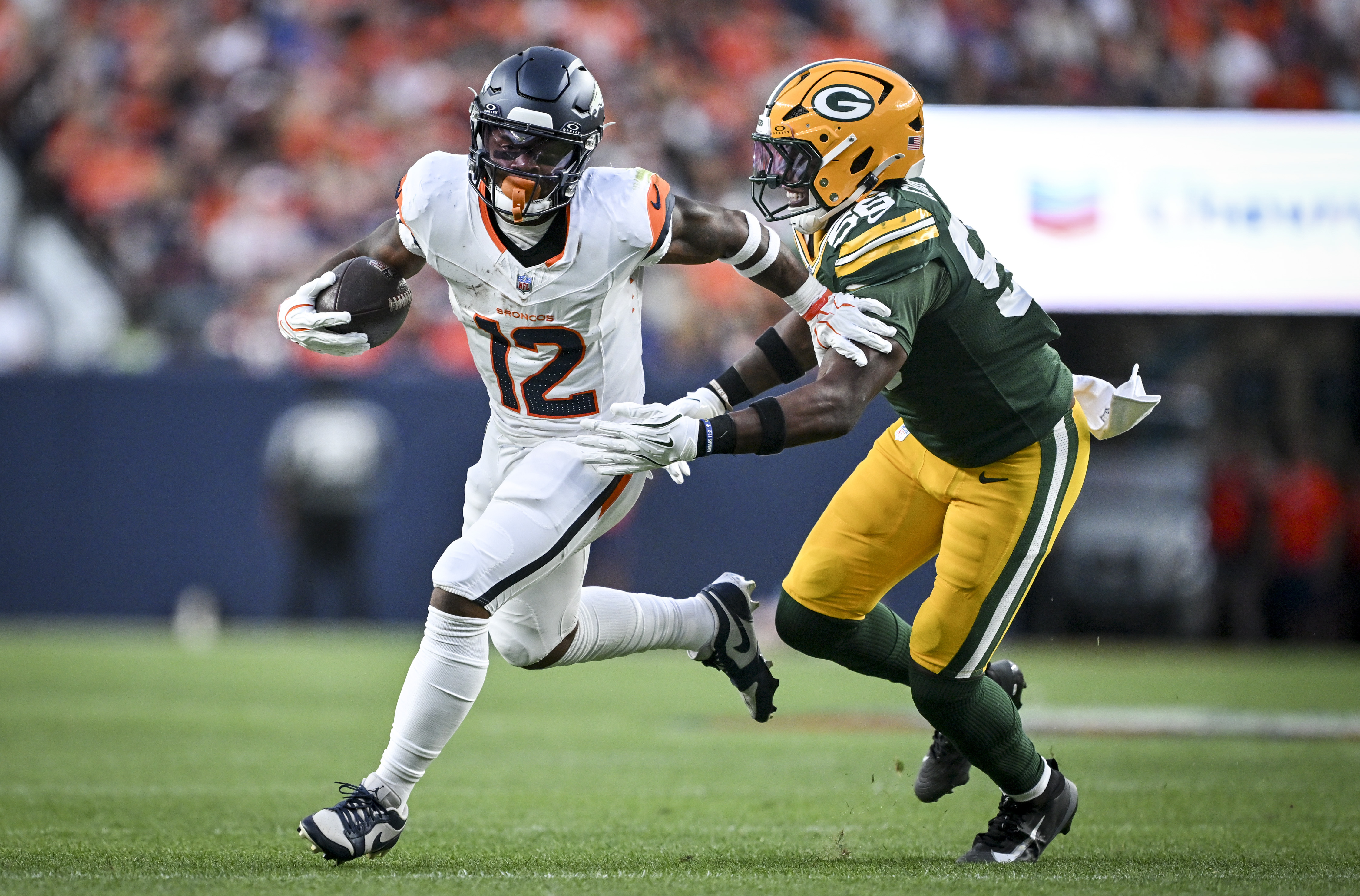 RJ Harvey (12) of the Denver Broncos attempts to shed a tackle by Edgerrin Cooper (56) of the Green Bay Packers during the first quarter at Empower Field at Mile High in Denver, Colorado on Friday, August 21, 2026. (Photo by AAron Ontiveroz/The Denver Post)