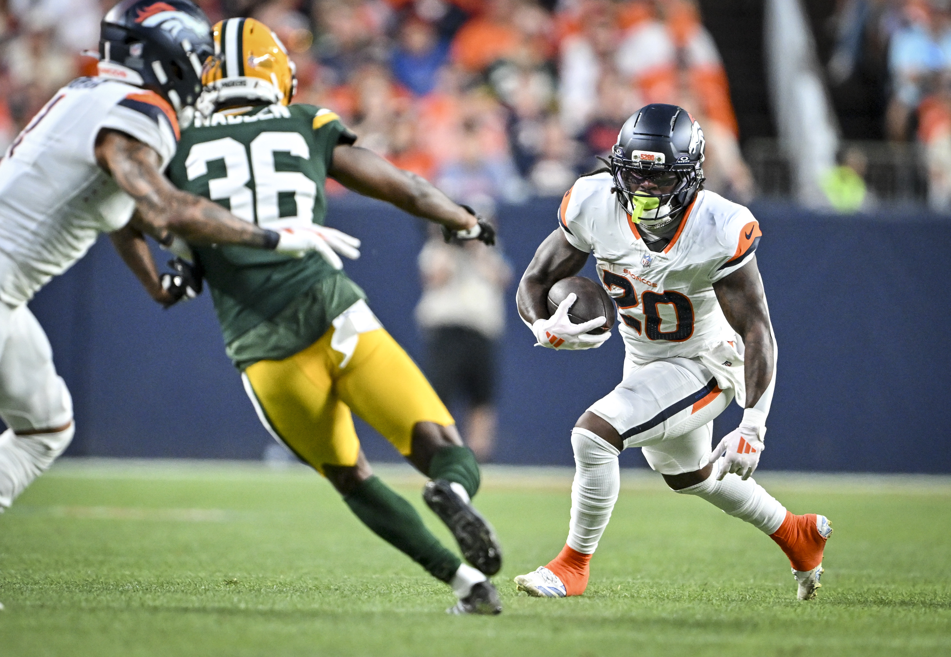 Jonah Coleman (20) of the Denver Broncos runs with the ball as Evan Engram (1) blocks Kamal Hadden (36) of the Green Bay Packers during the first quarter at Empower Field at Mile High in Denver, Colorado on Friday, August 21, 2026. (Photo by AAron Ontiveroz/The Denver Post)