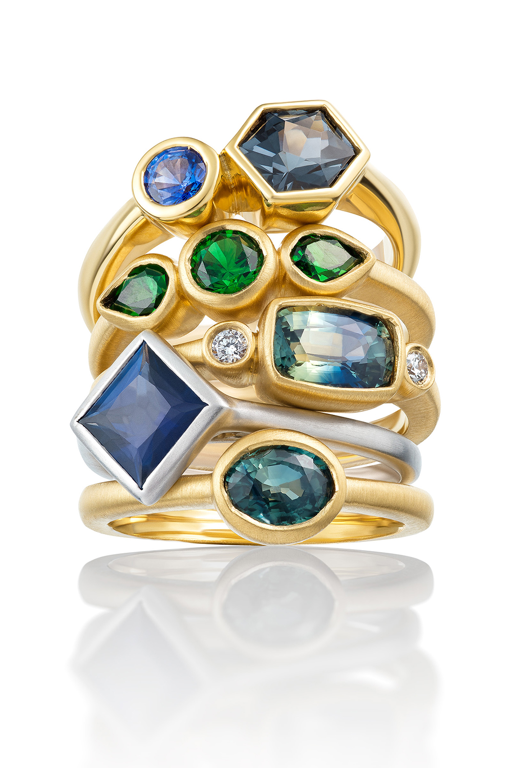Stunning stack of gold and silver rings with sapphires, emeralds and other blue & green ocean hues.