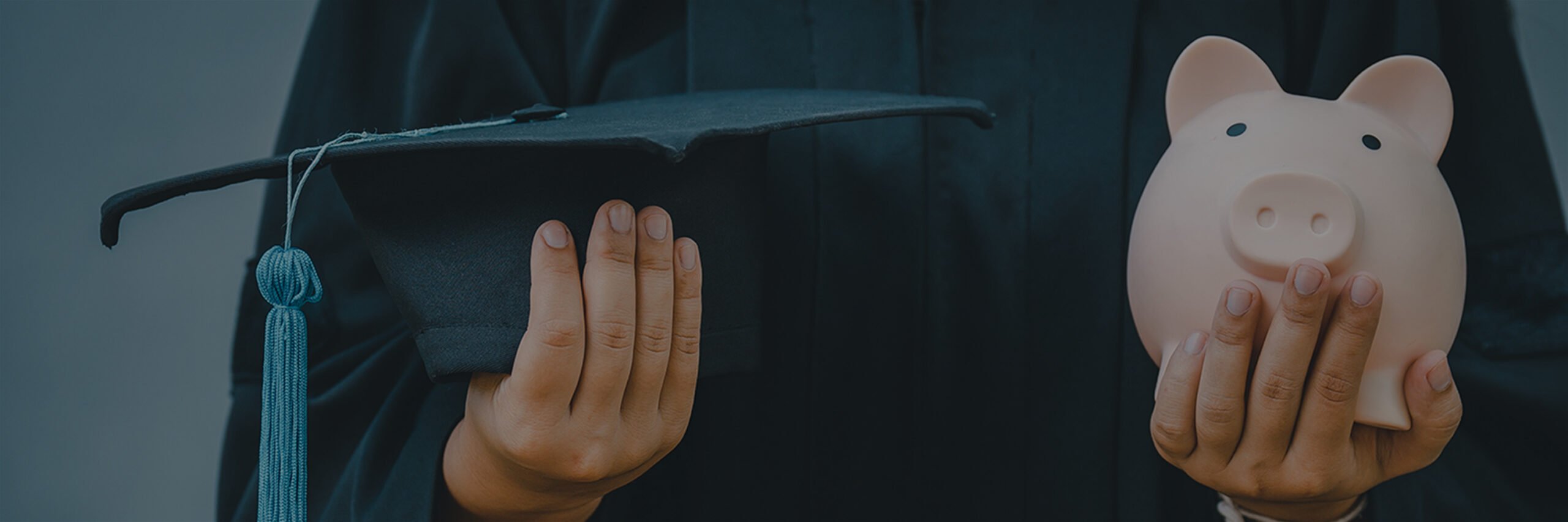 A person wearing graduation robes and holding a graduation cap in one hand and a piggy bank in the other.