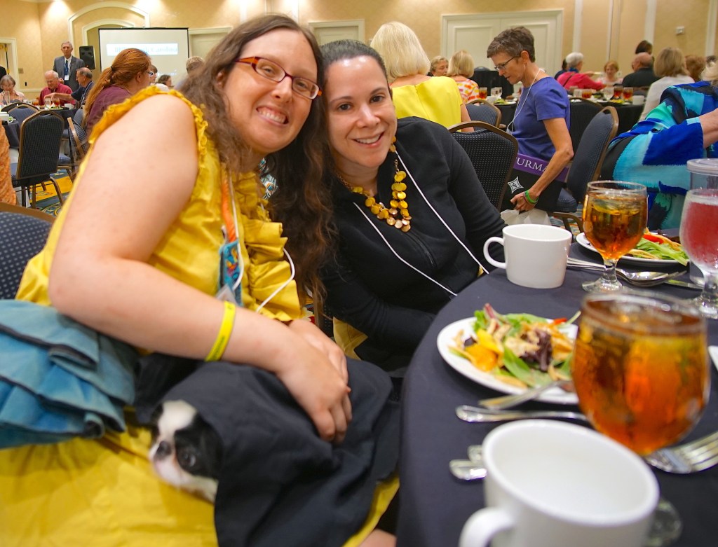 Veronica and Laura at lunch in matching yellow outfits, and Hestia underneath a napkin.