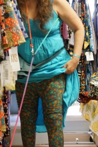 Veronica in a turquoise dress trying on some wildly colored leggings