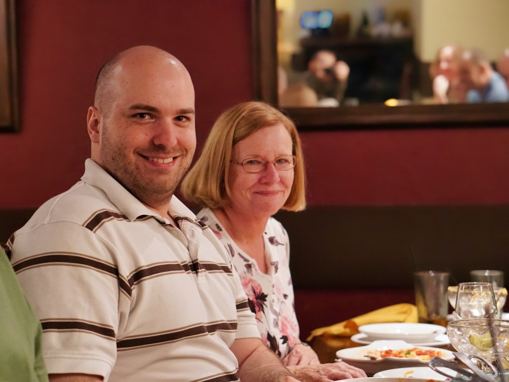 Tony and his mom, Suzanne.  Tony is wearing a striped shirt, and Suzanne has a floral shirt on.
