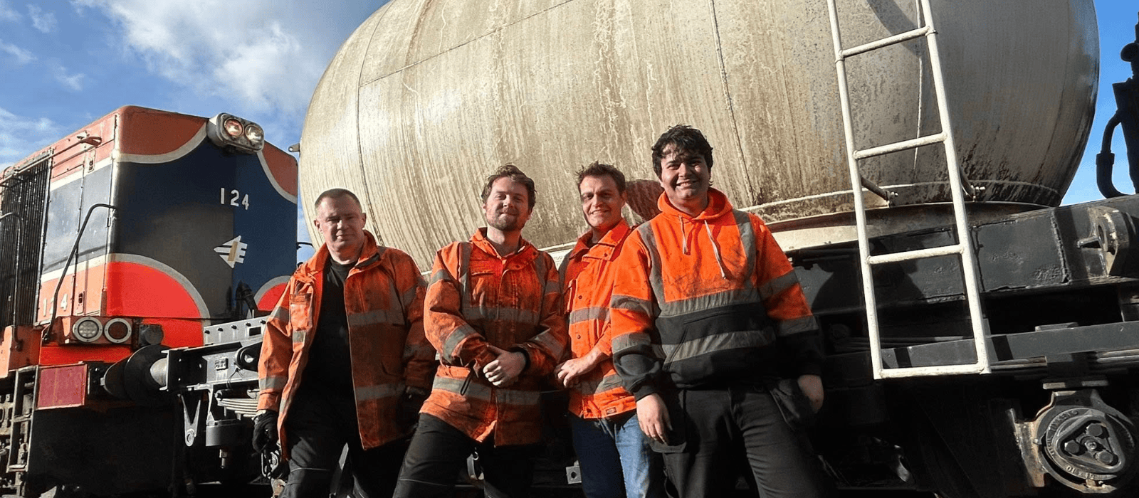 Four people pose beside a cement wagon.