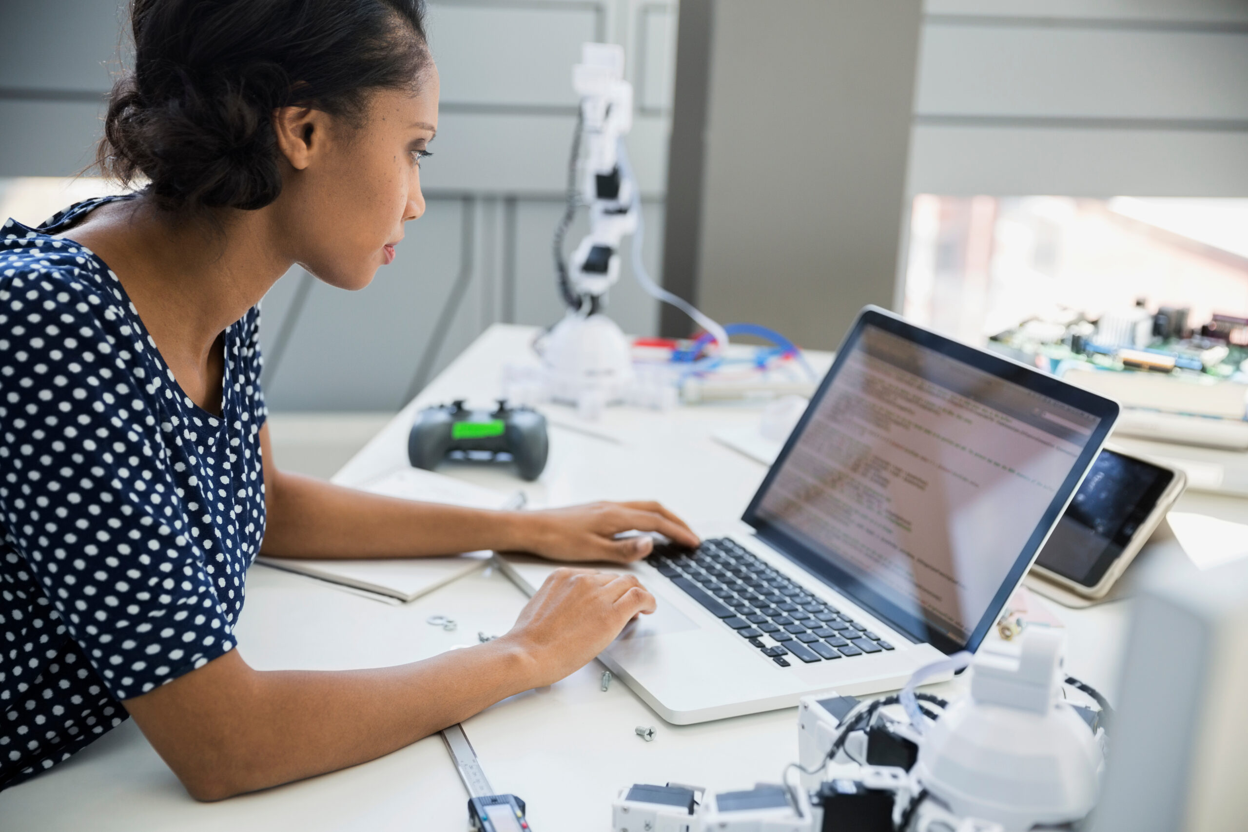 Engineer using laptop at desk with robotics