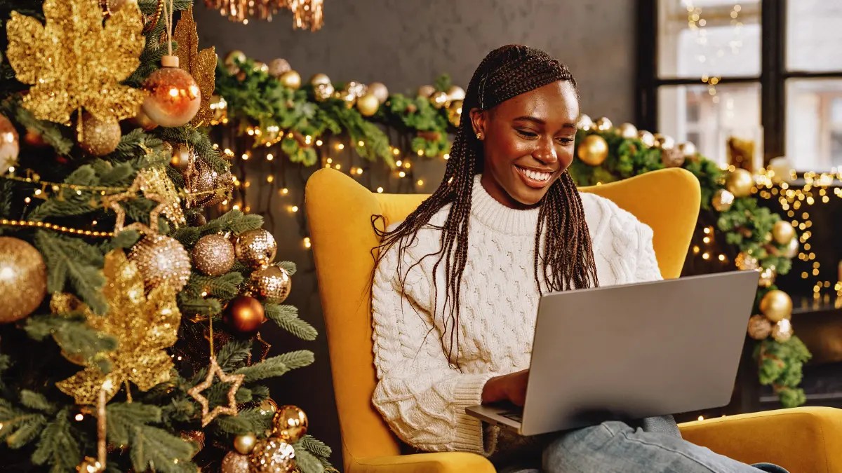Woman online shopping wit a Christmassy backdrop behind her