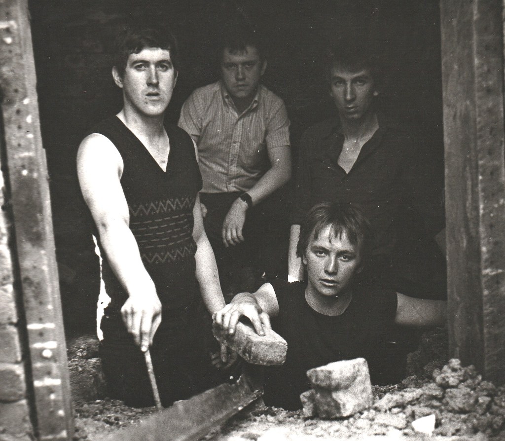 An old black and white photo of 4 young men in a punk band.