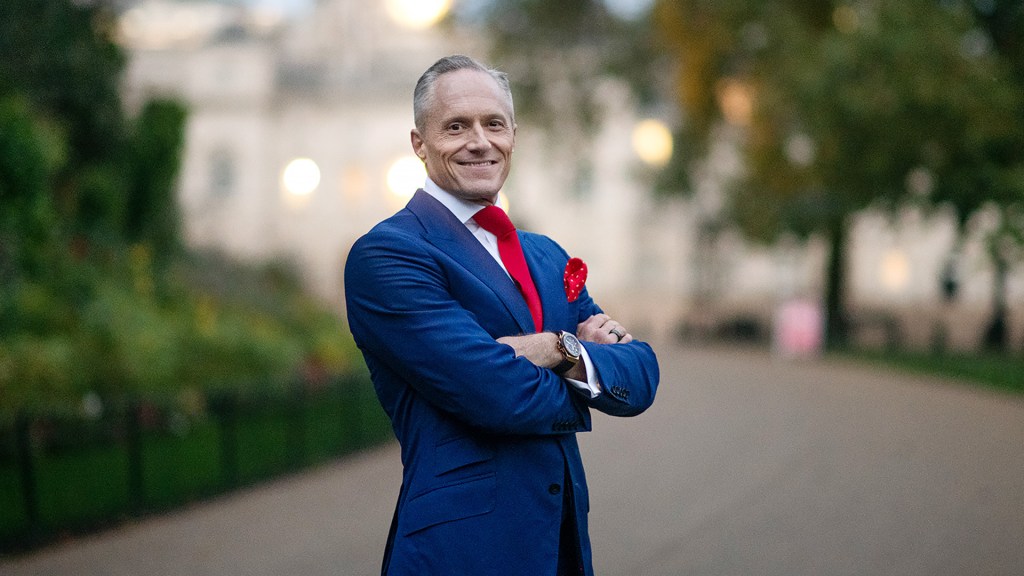 a man in a blue suit and red tie smiling