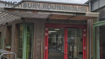 a wooden building with red and green doors and the words 'Highbury Roundhouse' above the doors