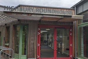 a wooden building with red and green doors and the words 'Highbury Roundhouse' above the doors