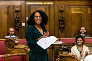 A woman smiling in a formal town hall room
