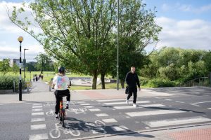 a cyclist cycling across a cycle crossing next to a pedestrian crossing