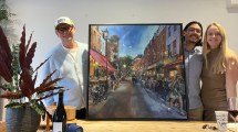 A vibrant street scene painting featuring cafes and people, surrounded by friends, with a decorative plant and bottles on the table.