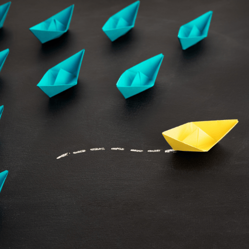 Multiple teal paper boats and one yellow paper boat going it's own direction