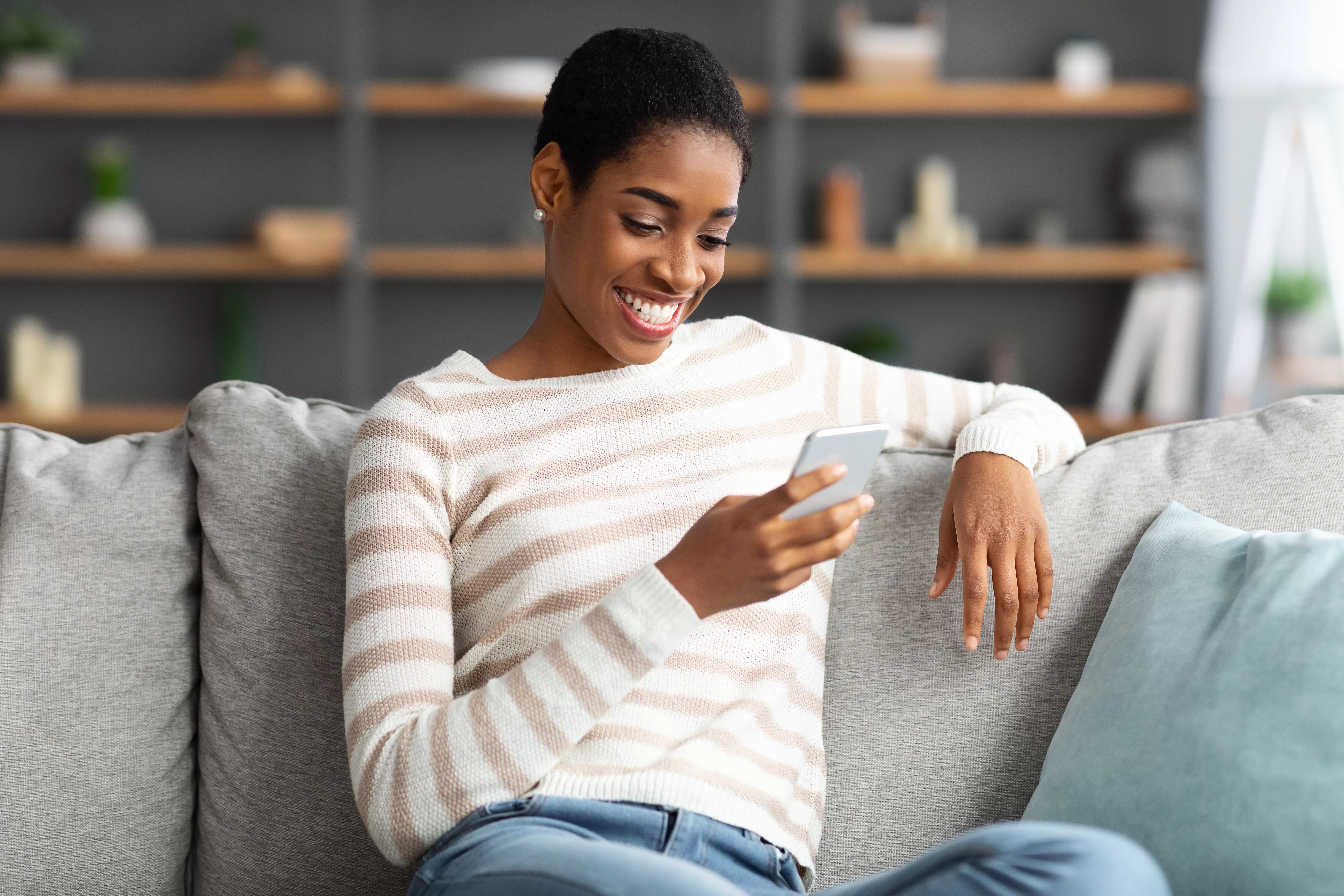 Smiling Black Woman Browsing New App On Smartphone While Resting At Home. Frequently Asked Questions: Premium Study Materials for Your Namibian Learners License Test