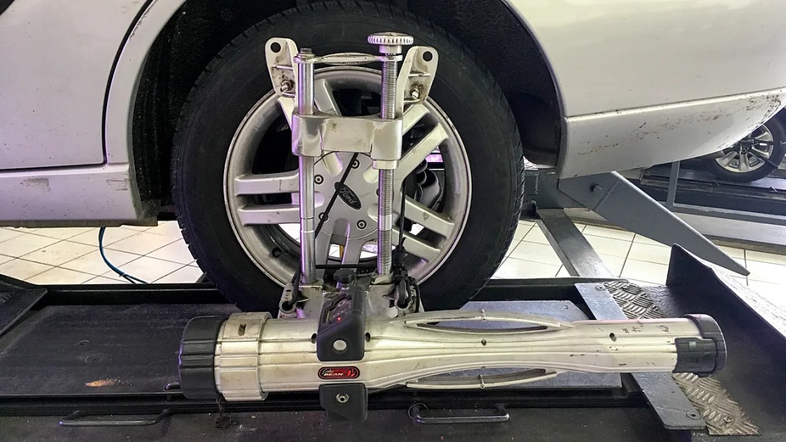 Wheel alignment sensor Wheel alignment sensor clamped to the front wheel of a silver Ford Focus on an alignment rack