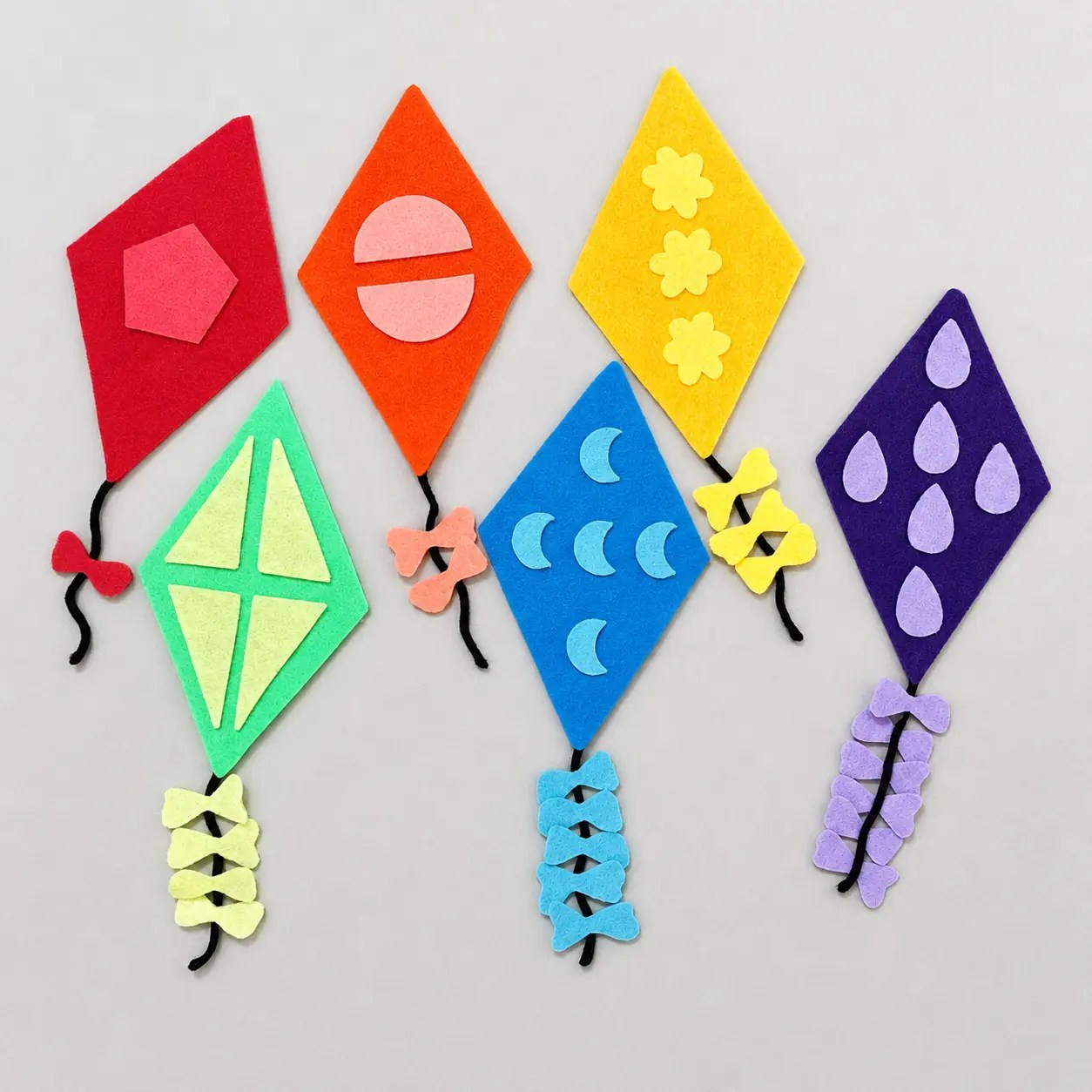 Flt board kites in roygbiv colors with shapes and progressively more bows per kite.