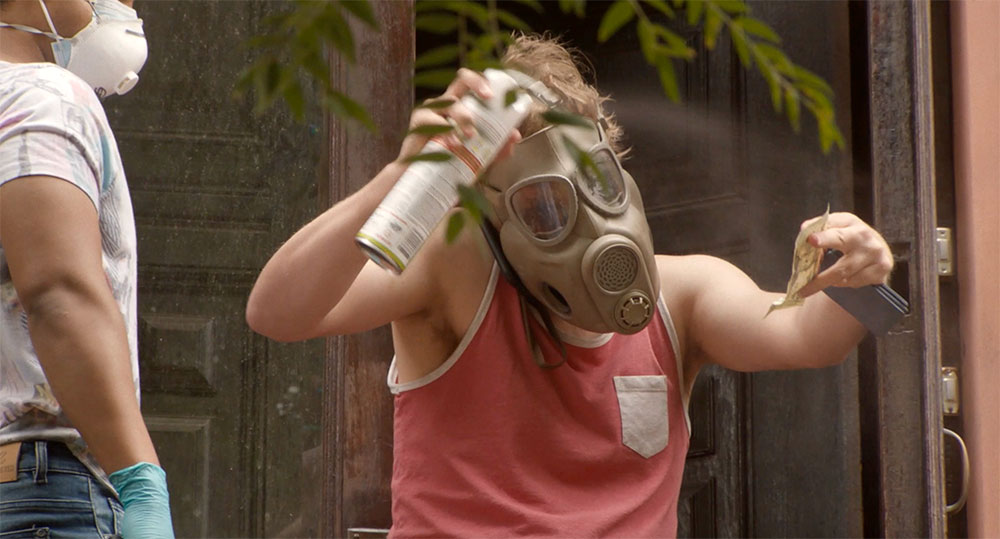 Terry in a gas mask as he sprays money with disinfectant.