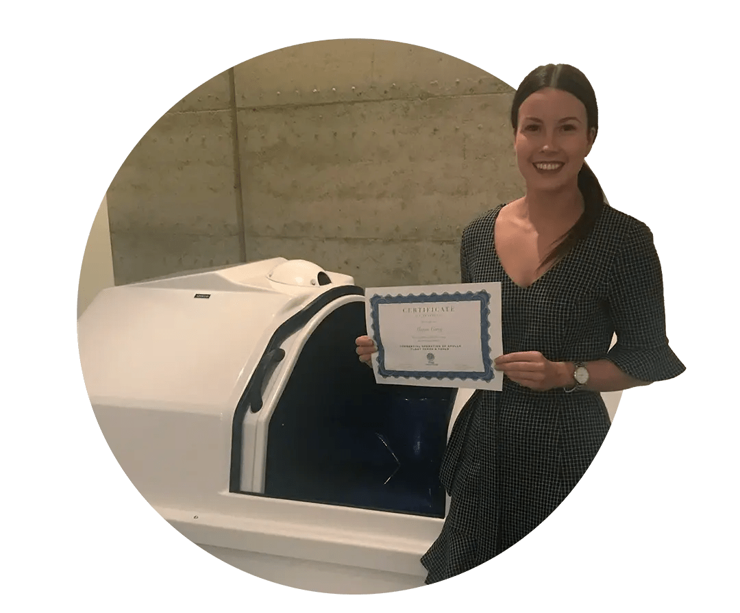 Photo smiling, professional female float centre owner standing in front of Apollo float tank holding certificate.