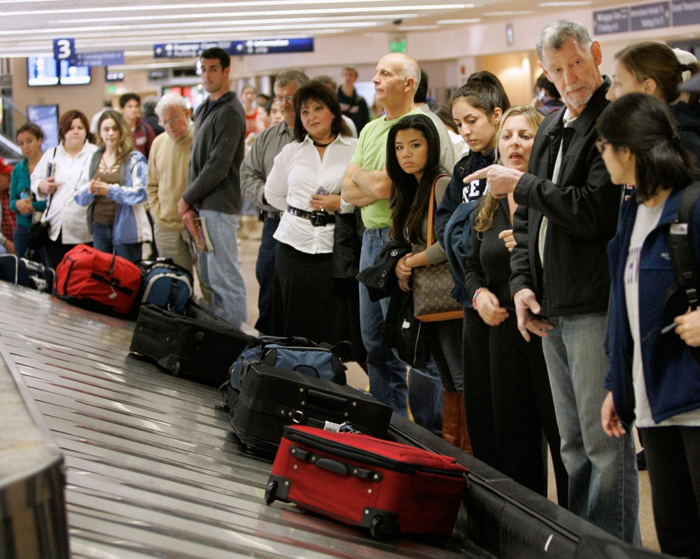 ** FILE ** In this Nov. 21, 2007 file photo, travelers line up to get their luggage in the Southwest Airlines baggage claim at the San Jose International airport in San Jose, Calif. It's time to think of the inside of your carry-on suitcase as real estate: Make the most of what you've got, keep it functional and make neatness count.  The carry-on bag could be the solution to some of the summer travel season's likely woes,  including checked baggage fees on American Airlines and possibly other carriers, but it also has the potential to cause headaches. (AP Photo/Marcio Jose Sanchez, file)