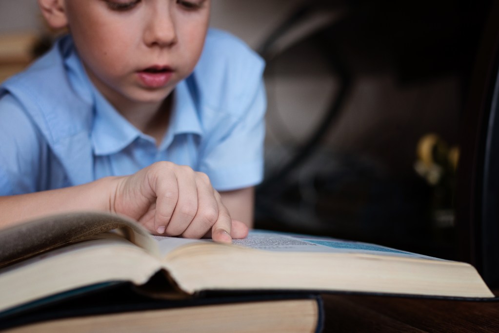 a boy is reading a book, a child is reading