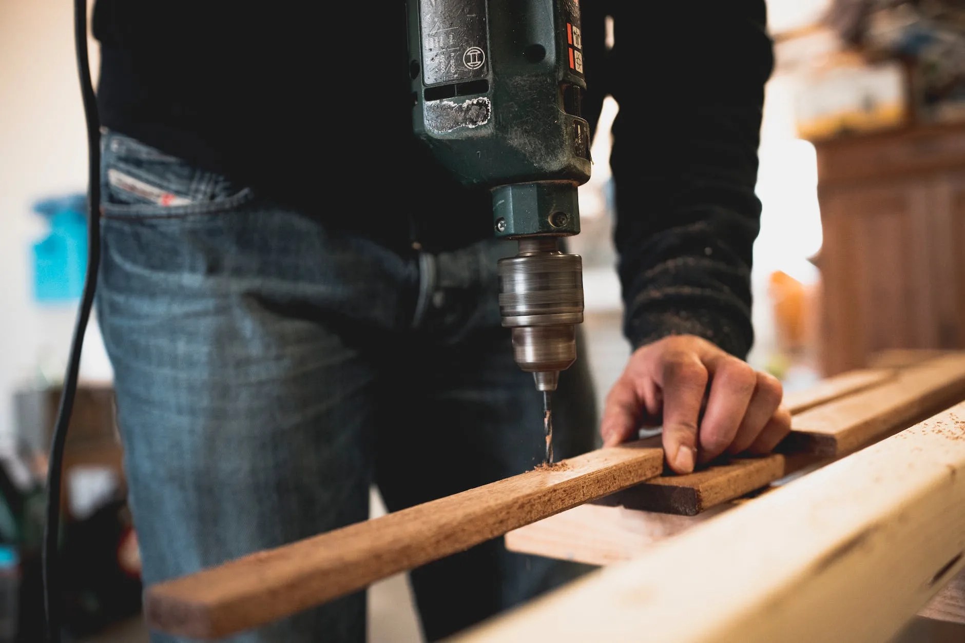 man holding wooden stick while drilling hole