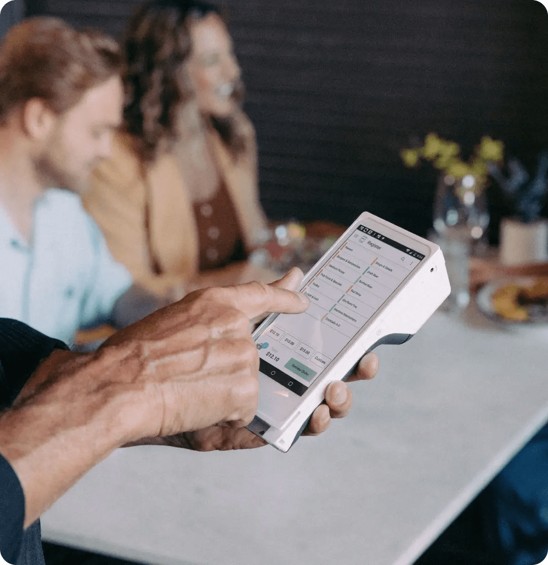 Customer using Clover Flex handheld POS system to place an order at a restaurant table