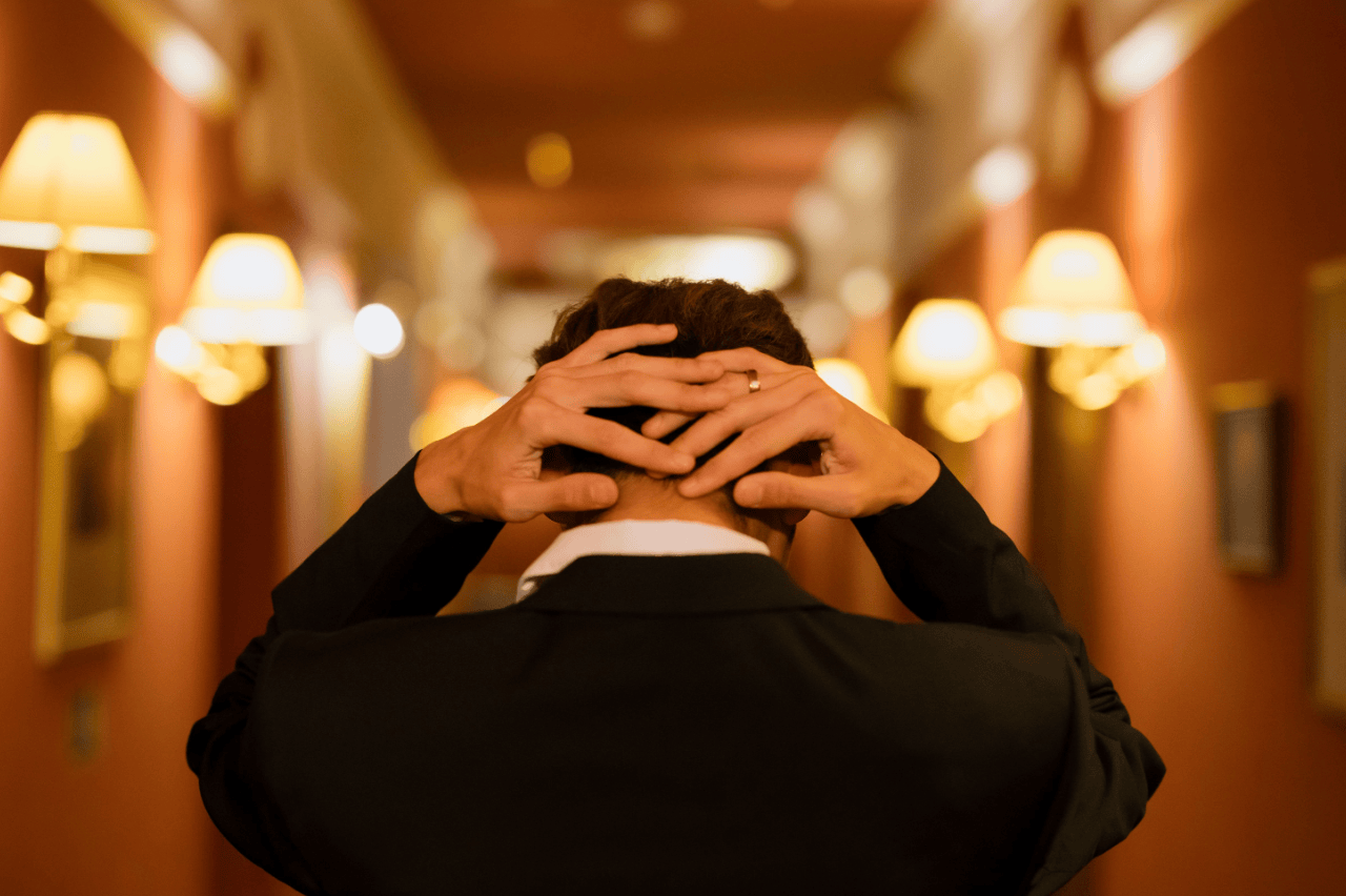 Stressed hospitality worker walking through hotel hallway, overwhelmed at work