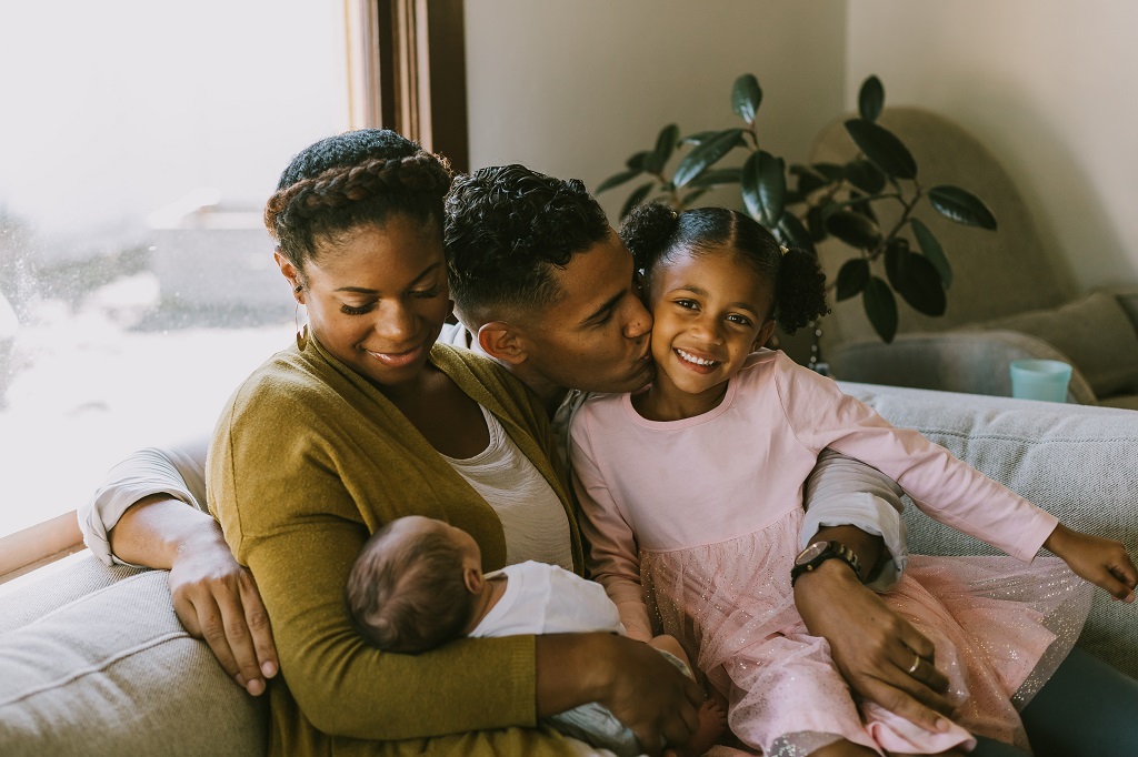 Family with newborn child on a couch