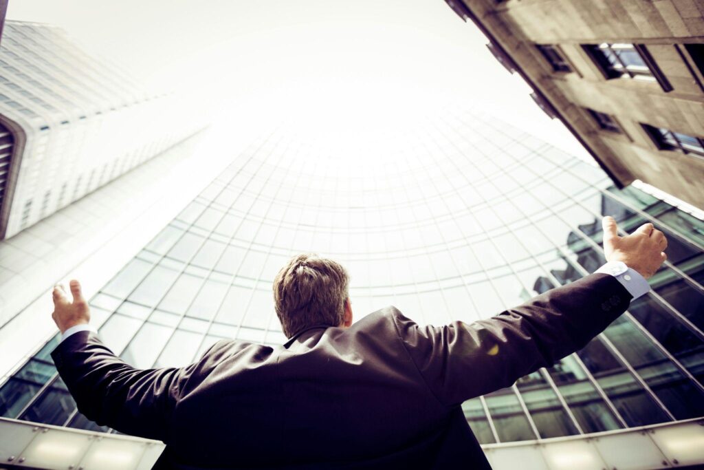 Man holding his hands up in triumph outdoors after improving retail business growth with ATM placement.