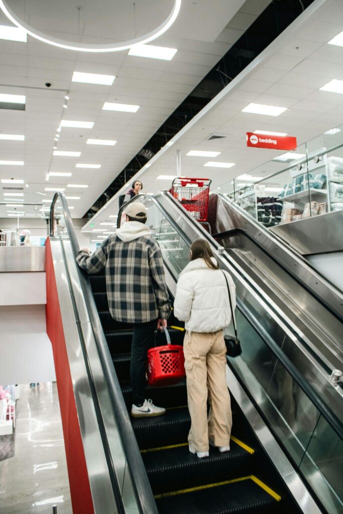 Two shoppers going up an escalator in a retail store where convenient ATM access can support customer spending.